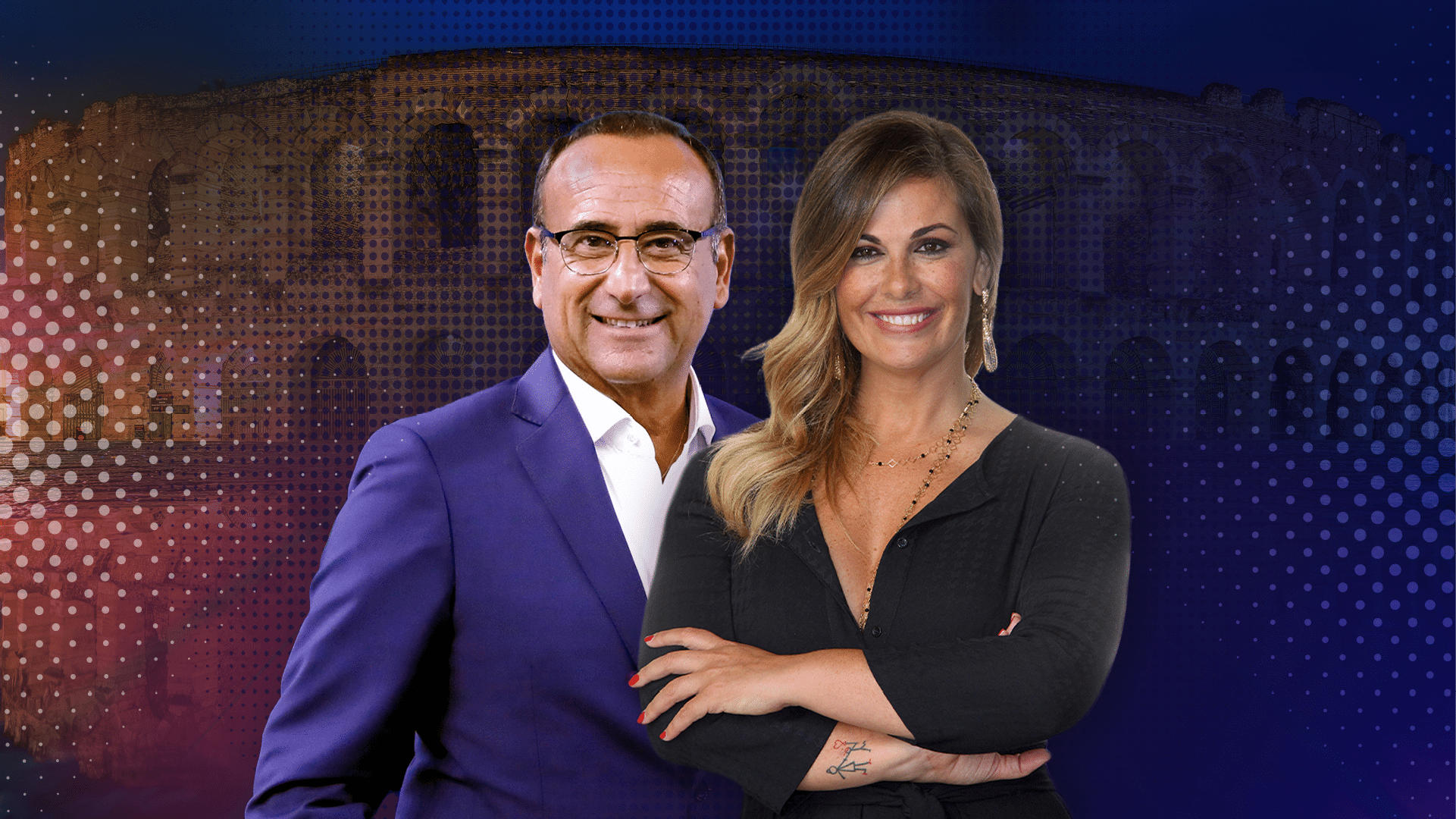 Two adults stand closely together smiling, with one wearing a dark suit and glasses and the other wearing a black top with arms crossed, against a colorful background featuring a large architectural structure. Descrizione generata da AI